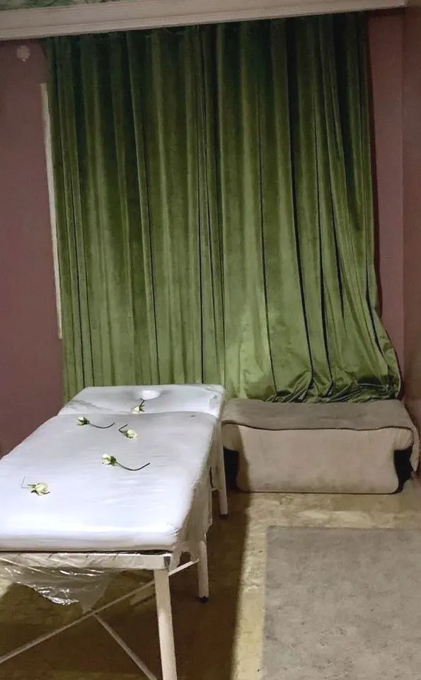 La cabine de massage — Murs mauves, rideau de velours vert, un ciel de feuillages peint au plafond.